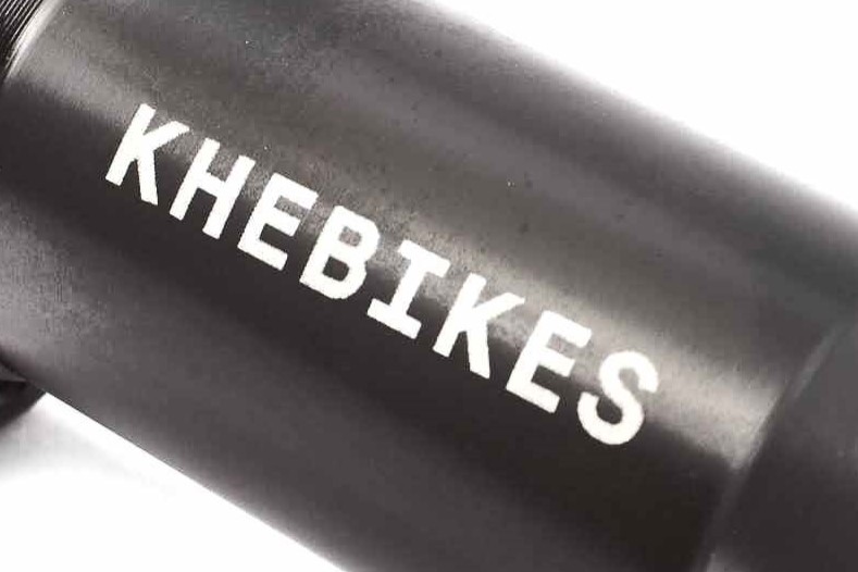 Nahaufnahme von weißer KHEBikes Aufschrift auf schwarzer Nabe Nahaufnahme von weißer KHEBikes Aufschrift auf schwarzer Nabe